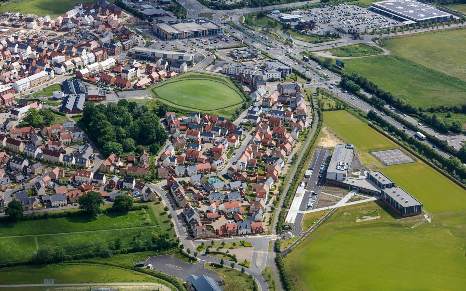 Aerial view of Phase Two South West Bicester – Kingsmere residential development showing completed housing, sports facilities, and surrounding landscape.