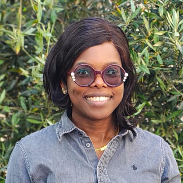 Bomi Ogunade, Chartered Engineer and Associate Director at Create Consulting Engineers, smiling outdoors wearing glasses and denim shirt.