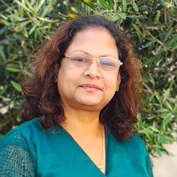 Sunanda Swain, Technical Director of the Sustainability team at Create Consulting Engineers, photographed outdoors against green foliage.