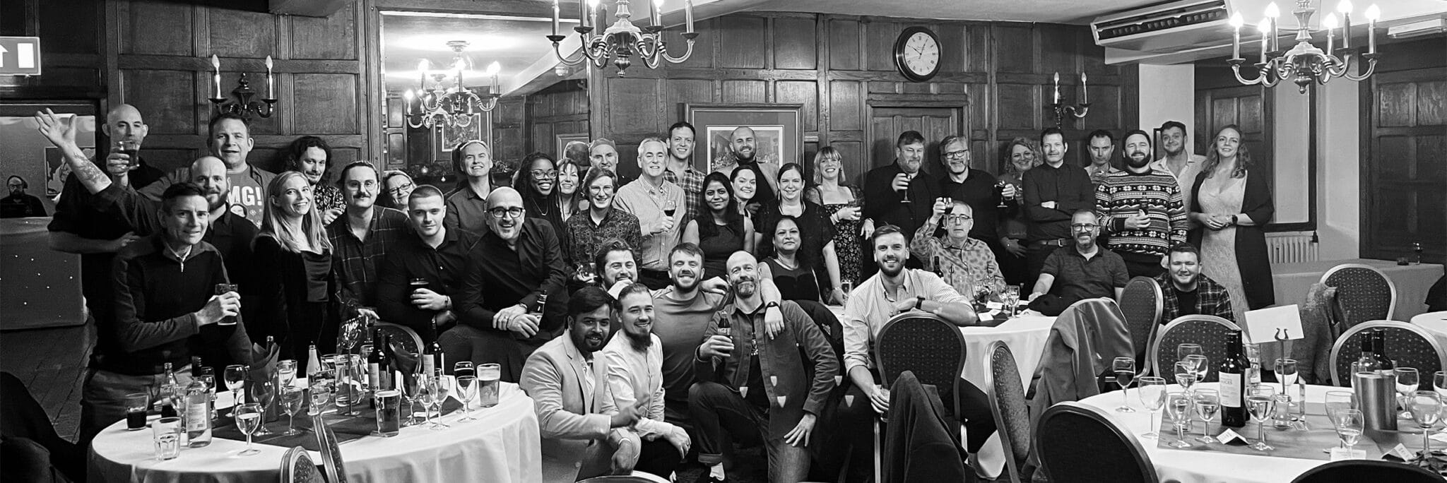 Create Consulting Engineers team gathering at formal event in elegant dining room with chandeliers and dark wood panelling.