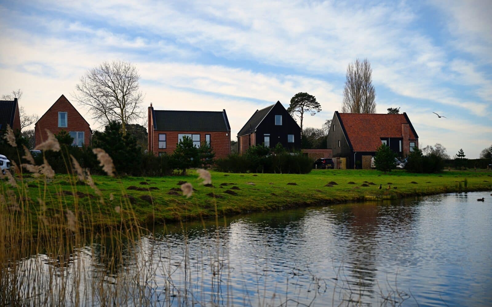 Residential properties beside a waterway in Ingoldisthorpe, Norfolk, demonstrating suburban development planning and environmental site context.