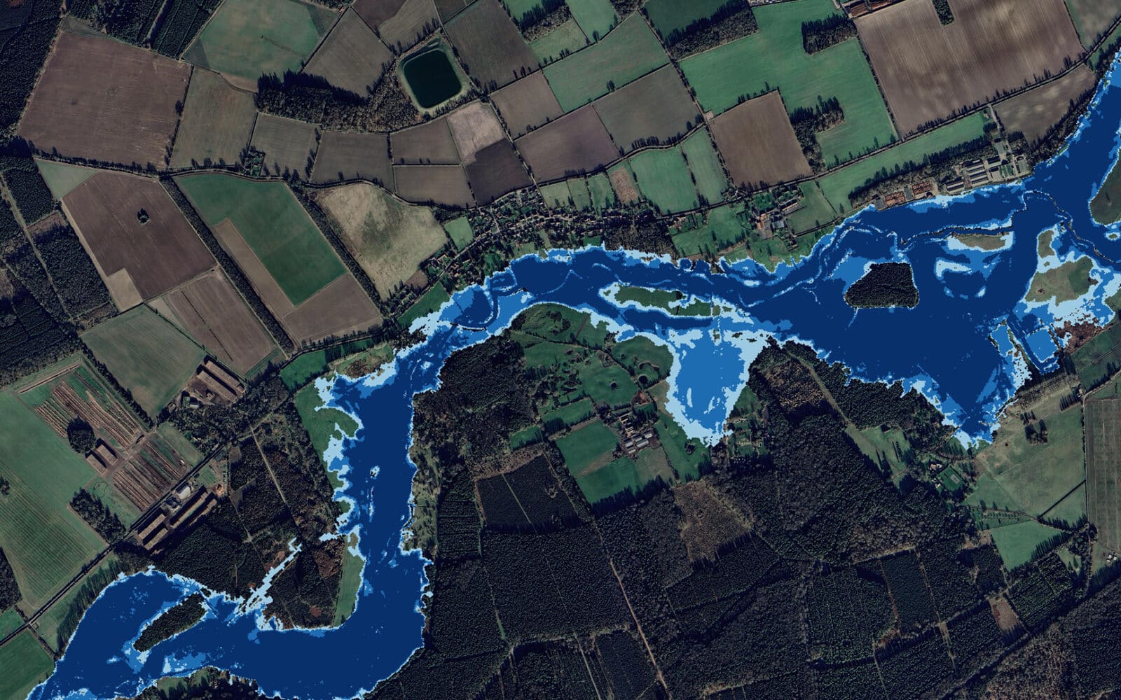 Aerial view of the River Thet and River Ouse confluence showing agricultural land and forested areas bordering the waterways.