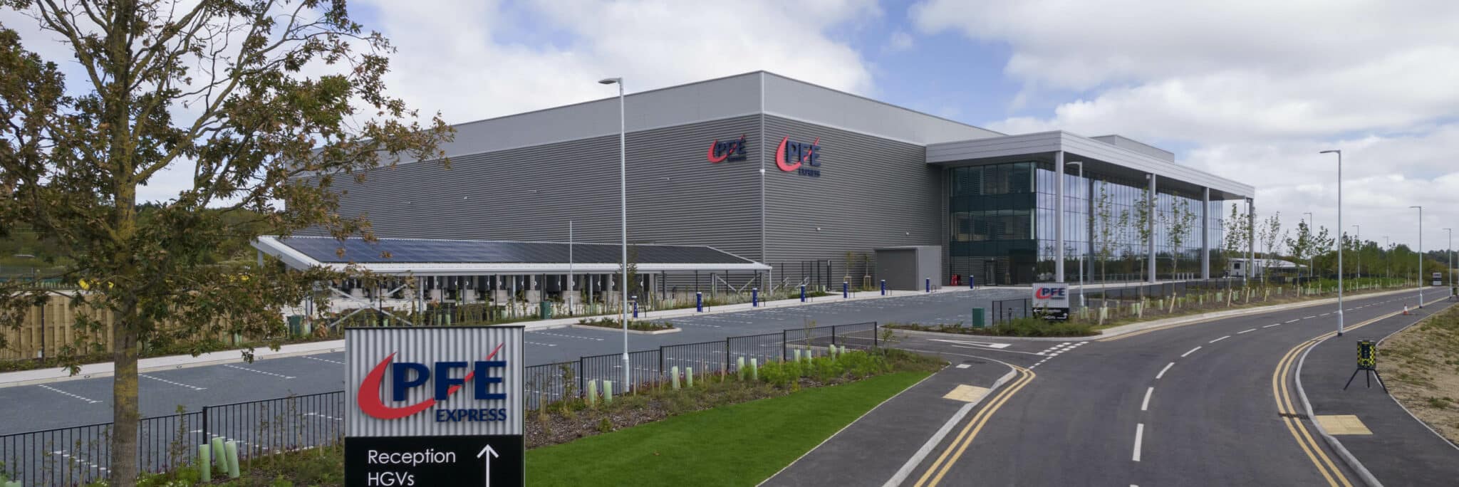 Modern industrial facility with grey corrugated cladding, glass frontage, and CPE Express signage visible on perimeter fencing and building entrance.